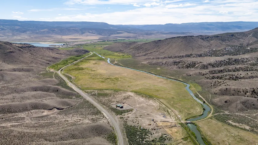 Expansive property featuring a winding river, a substantial green pasture, and a distant body of water