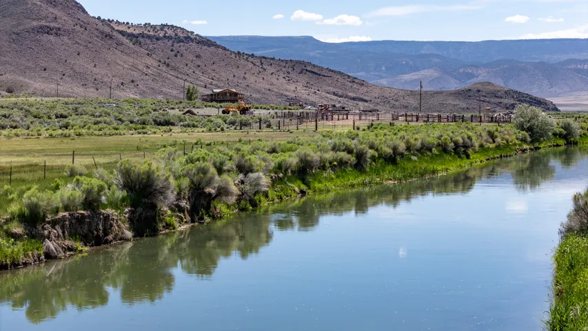 Expansive natural landscape featuring a prominent river, distant mountains, and varied vegetation