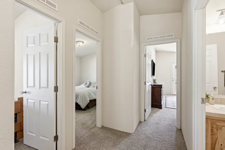 Central hallway with neutral-toned carpeting, white paneled doors, and recessed ceiling vents