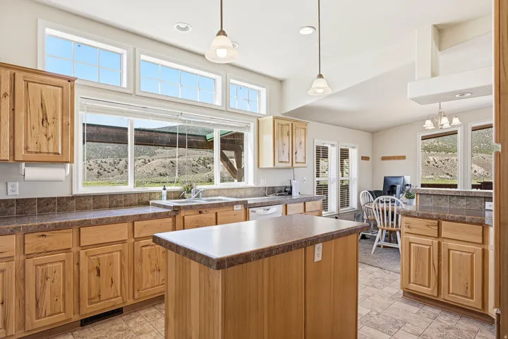 Kitchen featuring wood cabinetry, a central island, tile flooring, and ample natural light from multiple windows