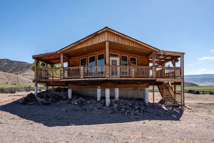 Wood-sided home featuring a full-width covered porch with wood railing and columns, multiple glass doors, and an exterior staircase