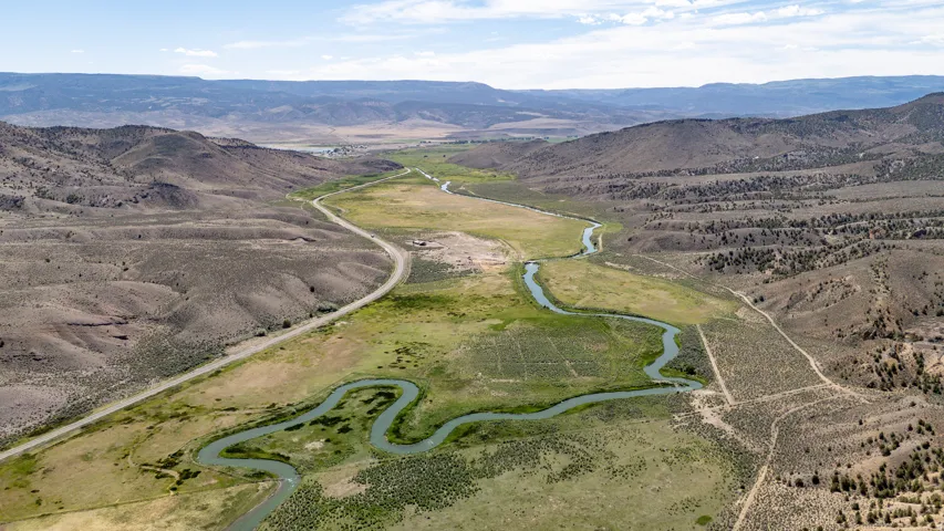 Expansive land parcel featuring a winding river, verdant riverbanks, and a visible roadway