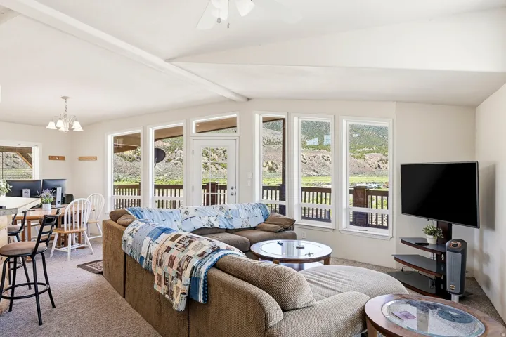 Open-concept living area with a vaulted ceiling and exposed beam