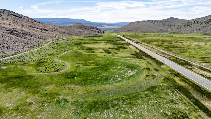 Expansive undeveloped terrain with varying topography, featuring a paved road and surrounding natural hillsides
