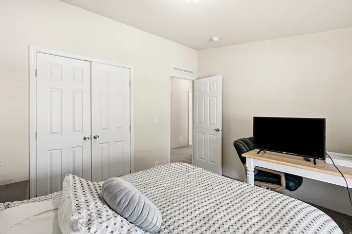 Bedroom featuring neutral wall color, carpeting, white paneled doors, and ceiling lighting