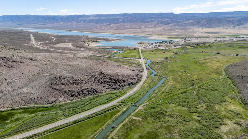 Expansive aerial showcasing a diverse landscape with a prominent body of water against a mountainous backdrop