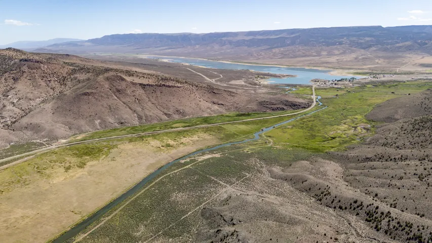 Expansive arid landscape featuring a prominent body of water, distant mountain ranges, and meandering waterways