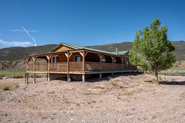 Rustic log cabin architecture featuring an expansive wrap-around porch