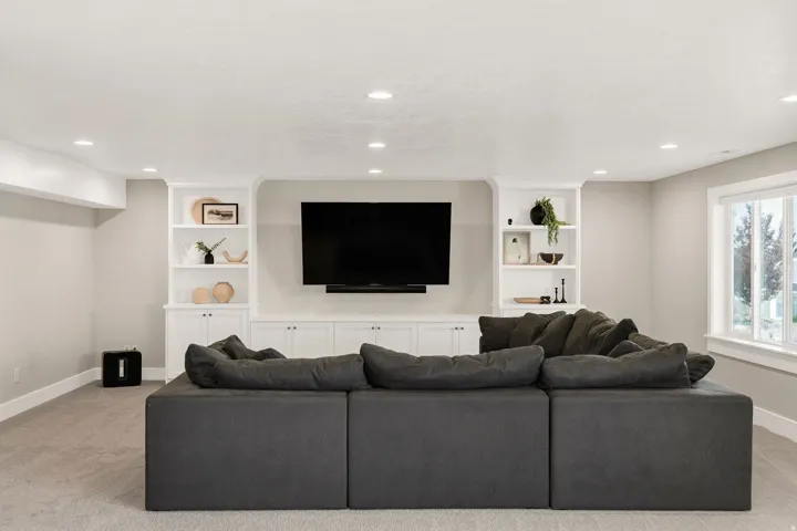 Recessed lighting illuminates a built-in entertainment center featuring shelving and lower cabinetry