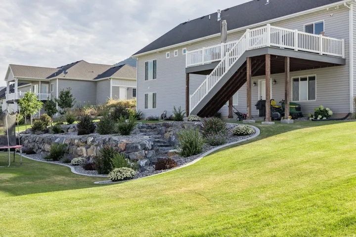 Multi-level landscaping featuring natural stone retaining walls and mature plantings