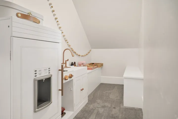 Carpeted attic space with a sloped ceiling and white walls
