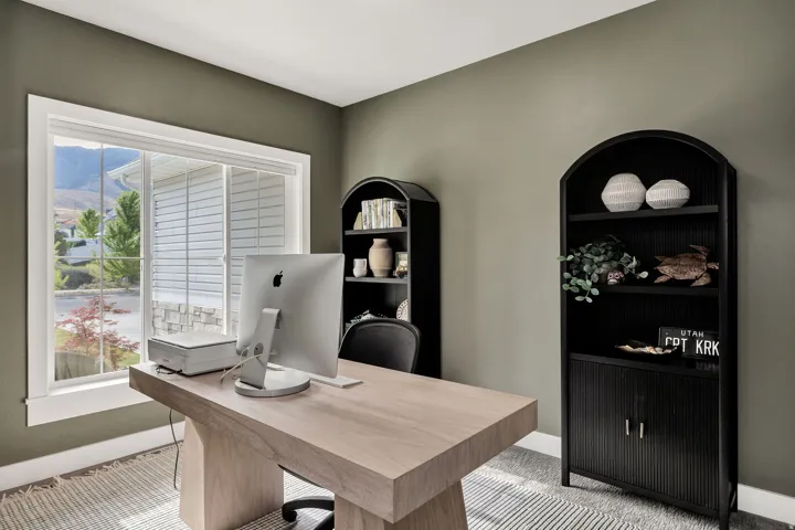 Spacious room featuring a large window, neutral wall color, and two built-in arched shelving units with lower cabinet storage