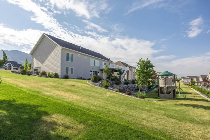Expansive tiered lawn with a rock retention wall and established landscaping