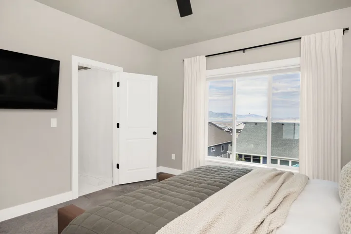Bright room featuring a large window with distant scenery, a built-in wall-mounted television, and a white interior door with black hardware