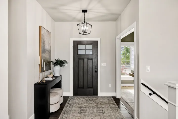 Entryway featuring a dark wood-finish door with glass panels, overhead geometric light fixture, wood-finish flooring, and light-toned walls