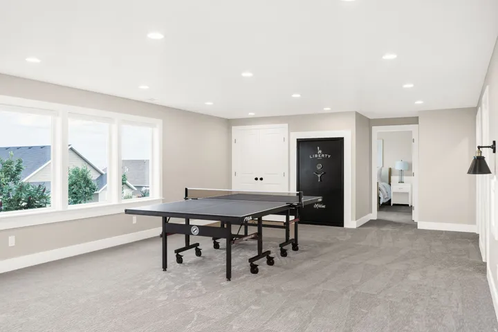Spacious room featuring light gray carpet flooring, recessed lighting, and three large windows with white trim