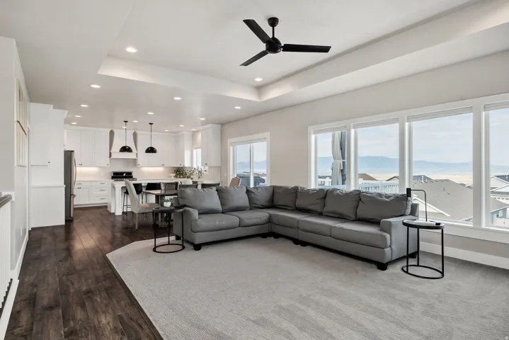 Open-concept living space featuring wood-finish flooring, recessed lighting, and a tray ceiling with a ceiling fan