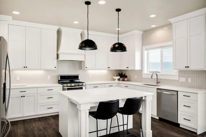 Modern kitchen featuring white cabinetry, dark wood-finish flooring, a central island, recessed lighting, and stainless steel appliances