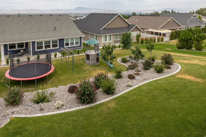 Expansive green lawn with established landscaping featuring decorative rock beds and mature plantings