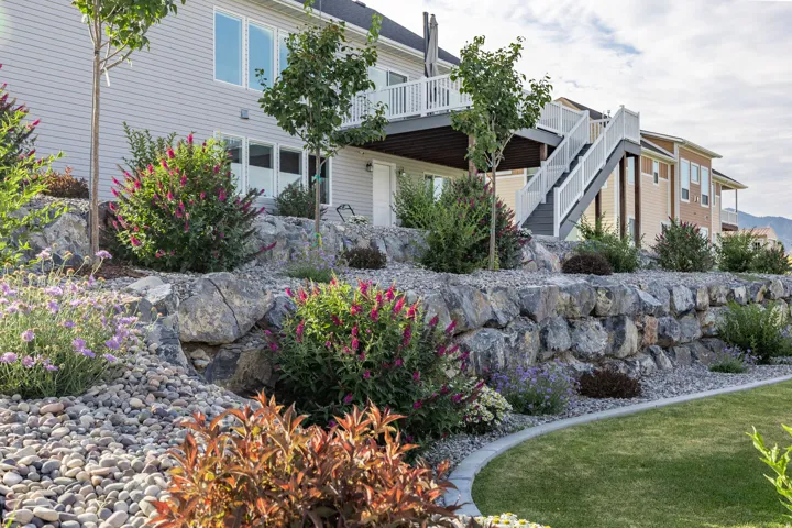 Terraced landscaping featuring a stone retaining wall, mature shrubs, and decorative rock beds