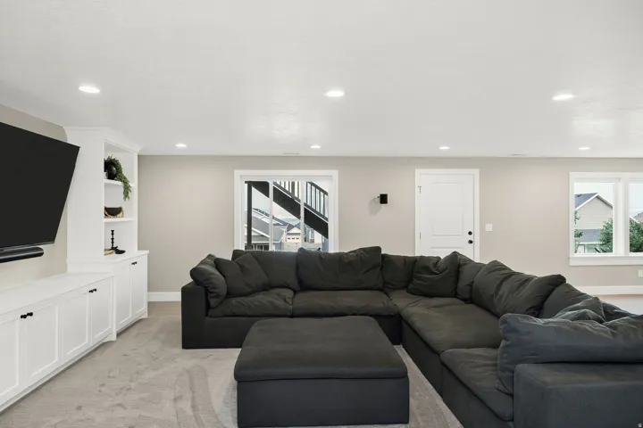 Built-in media console with storage and shelving, recessed lighting, neutral wall tones, light-toned carpeting, and white trim