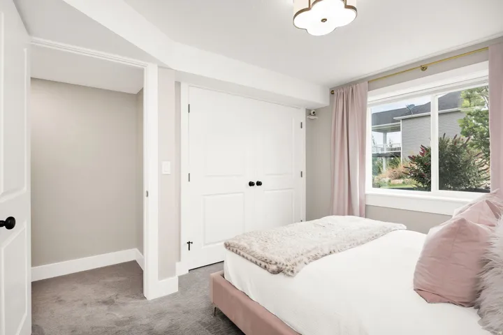 Carpeted interior with a large window, white trim, and a built-in closet with double doors