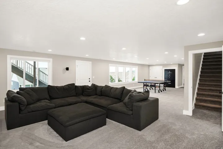 Spacious lower-level living area featuring recessed lighting, a sliding glass door, and a multi-pane window row