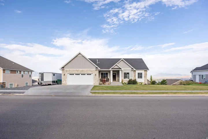 Ranch-style residence featuring a prominent two-car garage, stone and siding exterior, front porch entry, and a well-maintained front lawn