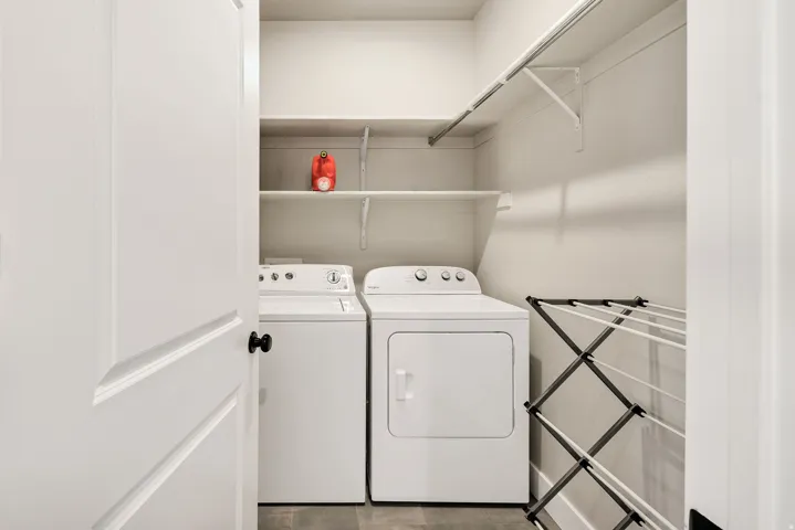Dedicated laundry area featuring a washer and dryer, built-in shelving, and a hanging rod