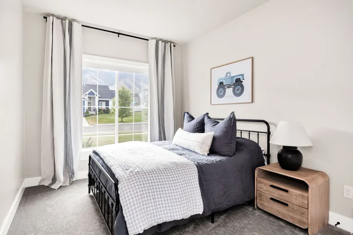 Bedroom featuring a large multi-pane window, light gray wall paint, and gray carpet flooring