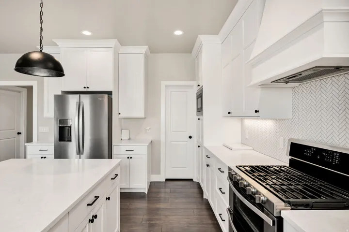 Contemporary kitchen featuring white cabinetry, a large island with a solid surface countertop, stainless steel appliances, and wood-finish flooring