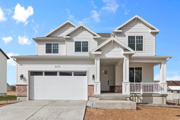 Contemporary white siding exterior featuring a covered front porch with white railings, a two-car garage, and brick accent detailing