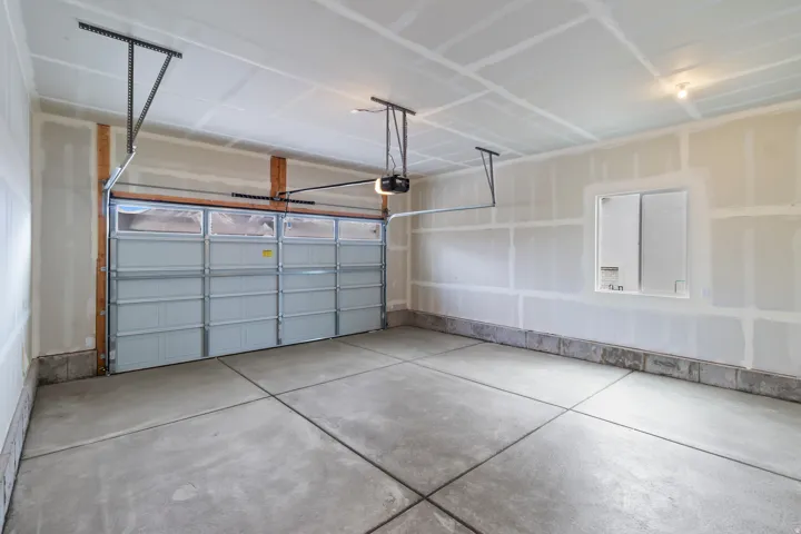 Spacious garage featuring a concrete floor, overhead lighting, and an automatic garage door opener