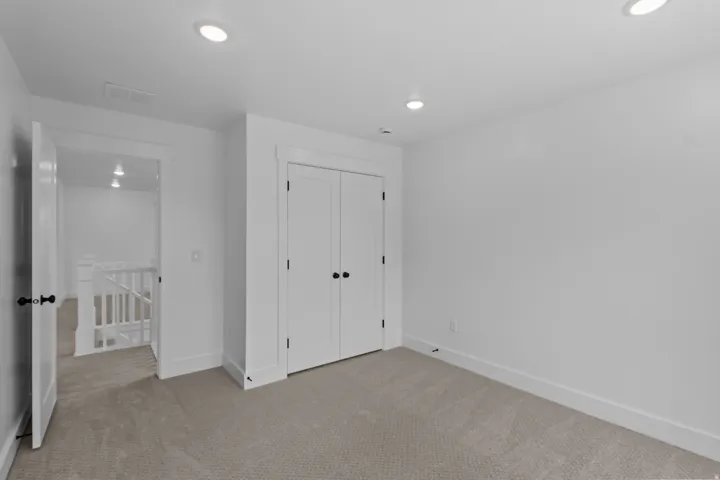 Carpeted room with recessed lighting, white walls, and a bi-fold closet door