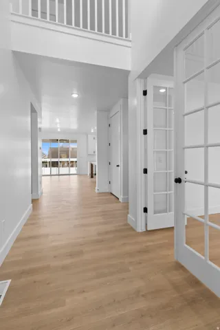 Foyer featuring wood-finish flooring, white trim, recessed lighting, and a prominent second-story balcony with white railing