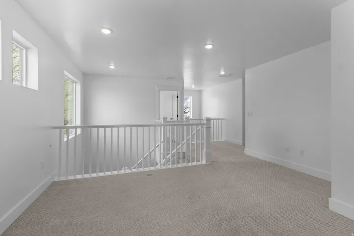 Spacious upper-level landing with neutral carpeting and bright white walls