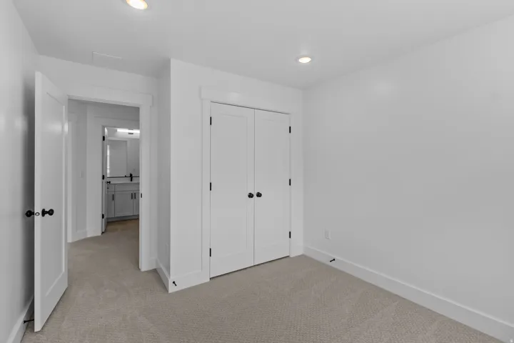Carpeted room with recessed lighting and a closet featuring double doors with matte black hardware