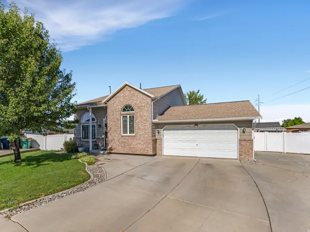 Exterior featuring a brick facade, siding, arched windows, an attached garage, and a concrete driveway