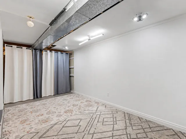 Unfinished room featuring white walls, baseboard trim, and exposed ductwork
