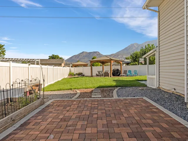 Brick paver patio with a herringbone pattern, bordered by gravel and a manicured lawn