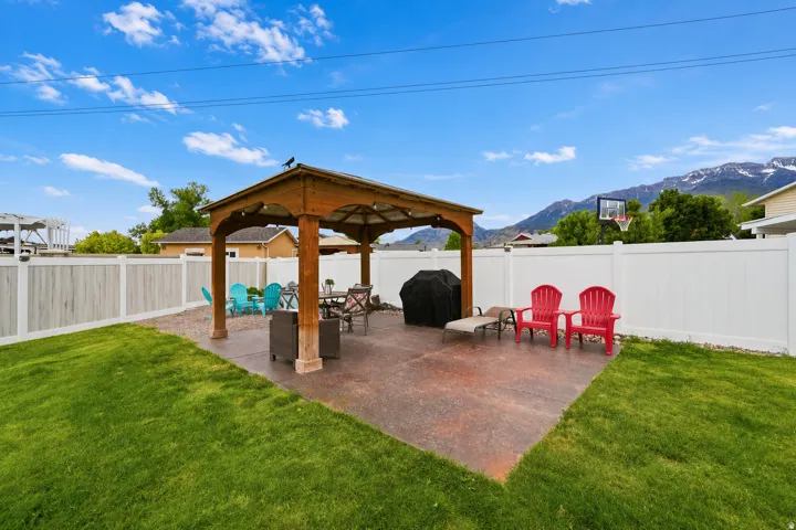 Spacious backyard featuring a wood-beam gazebo, concrete patio, and manicured lawn
