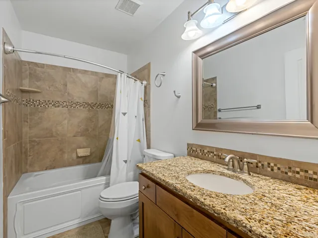 Bathroom vanity featuring a granite countertop with an integrated sink, brushed nickel faucet, and a large framed mirror