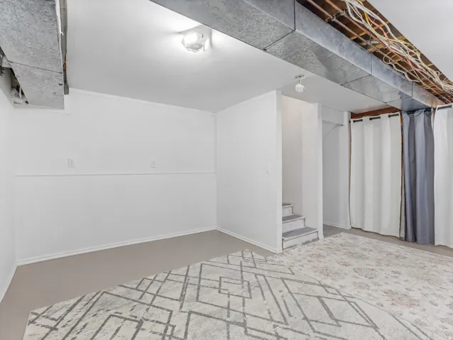 Finished interior space featuring light gray flooring, white walls, and exposed ductwork