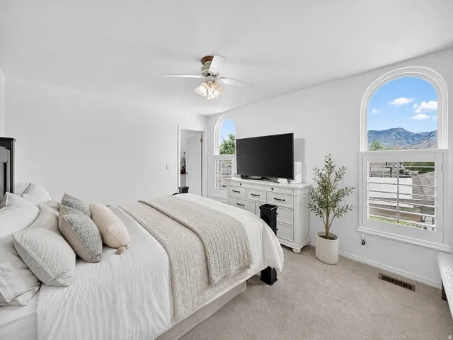 Bright room featuring two arched windows with mountain scenery, plantation shutters, and light-toned carpeting