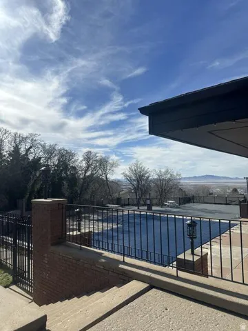 Outdoor pool area featuring a dark safety cover, surrounding concrete patio, and black metal fencing