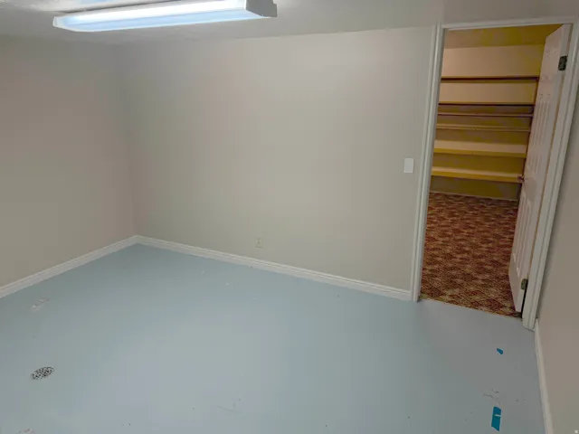 Room featuring light-toned walls, white baseboards, and light blue flooring