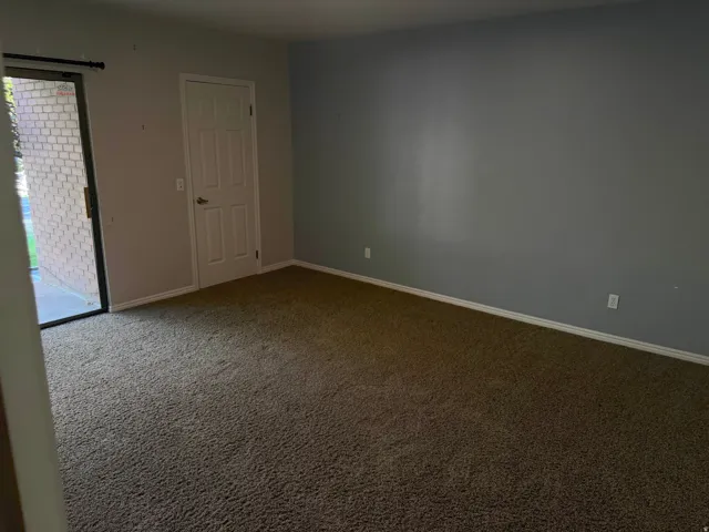 Carpeted interior space featuring a sliding glass door providing exterior access