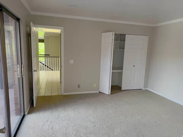 Carpeted room featuring a built-in closet with bifold doors and shelving, crown molding, and recessed lighting