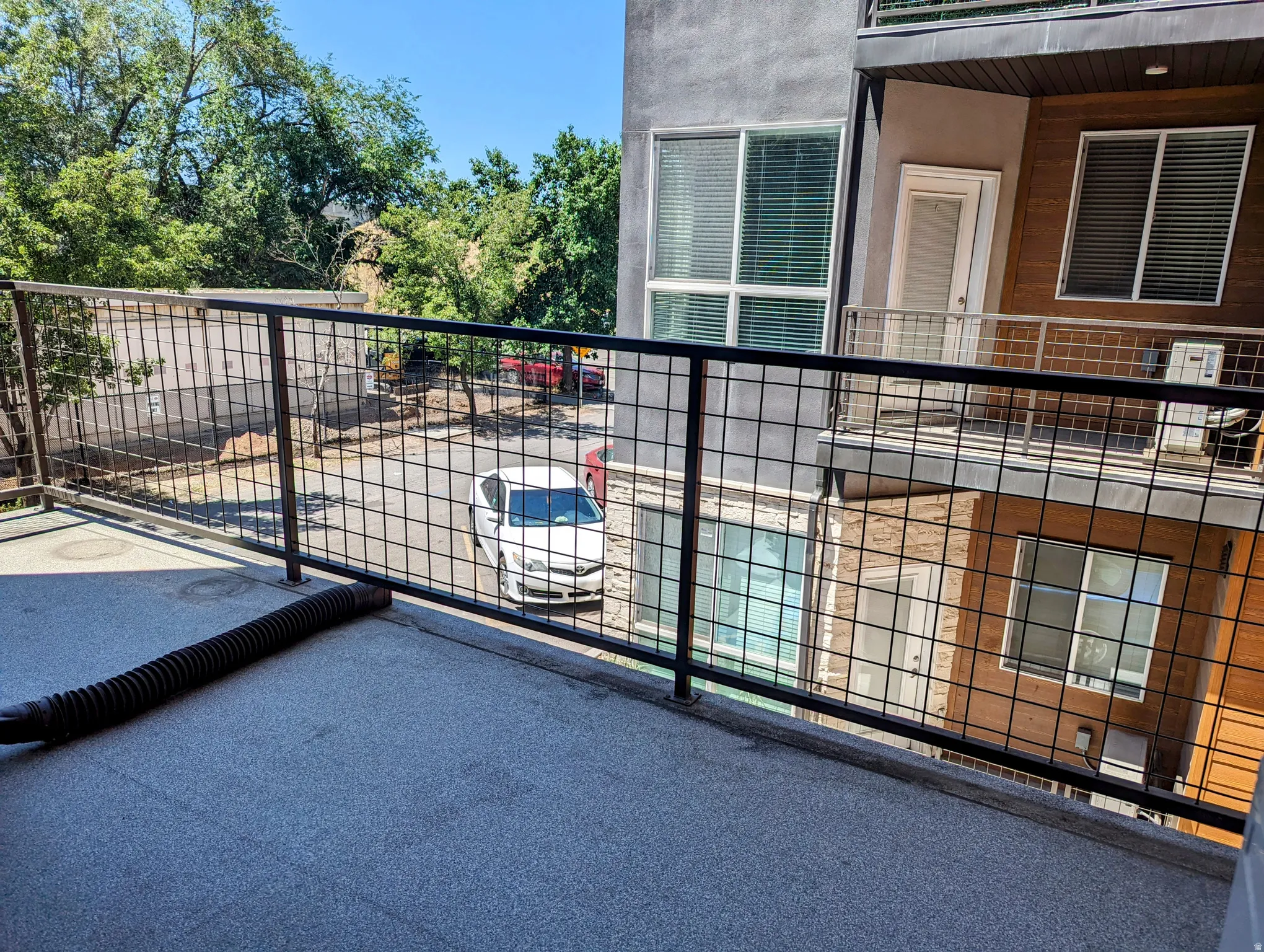 Private balcony with concrete flooring and a metal grid railing