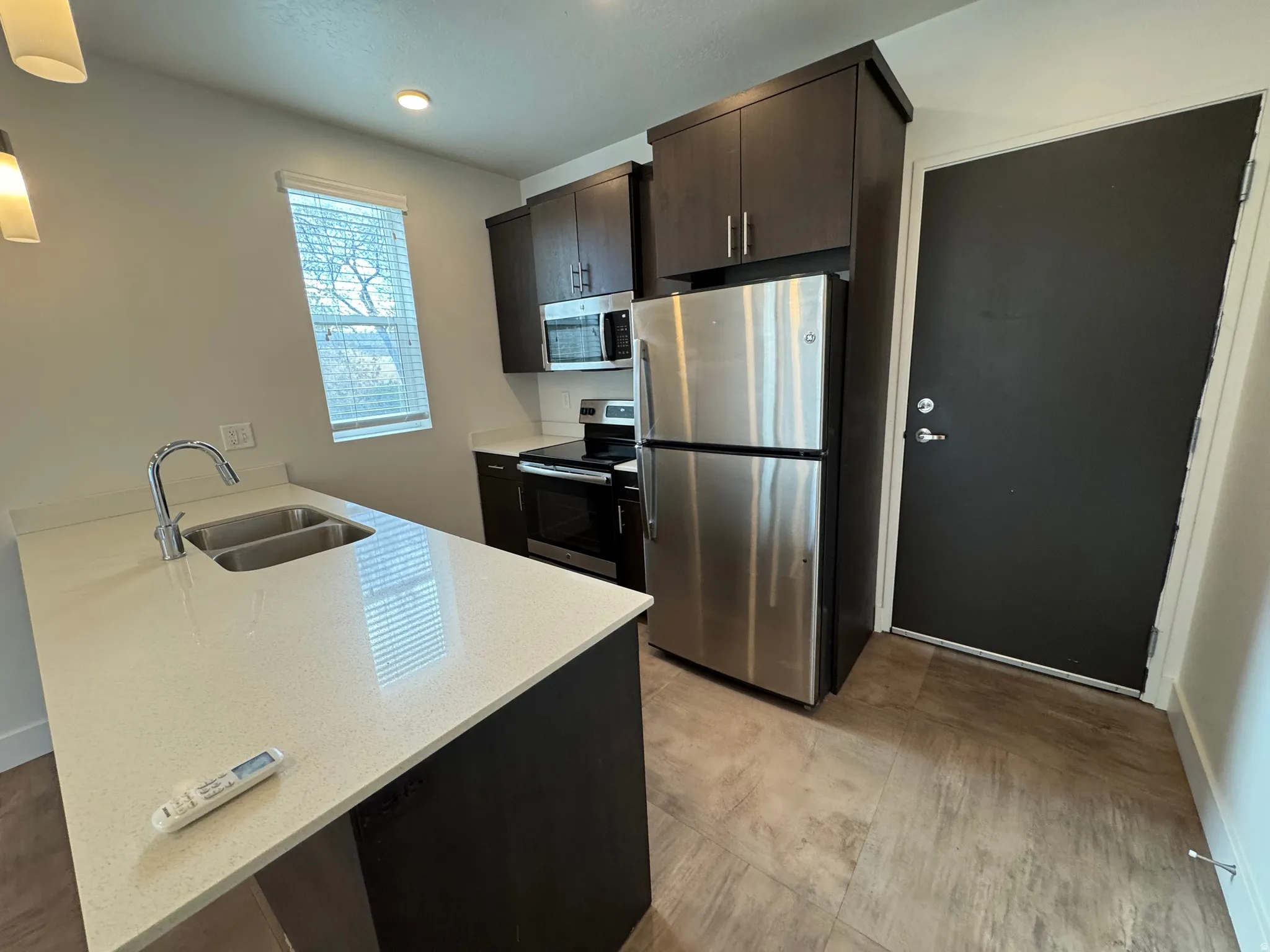 Modern kitchen featuring dark wood-finish cabinetry and stainless steel appliances